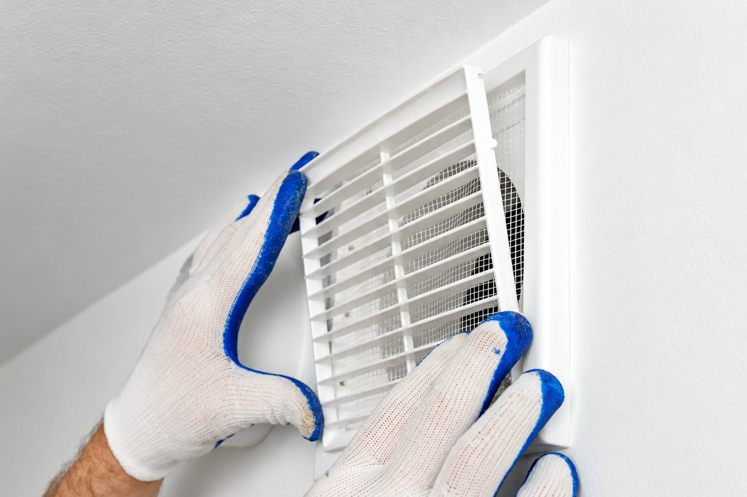 Mains gantées qui posent une grille de ventilation
